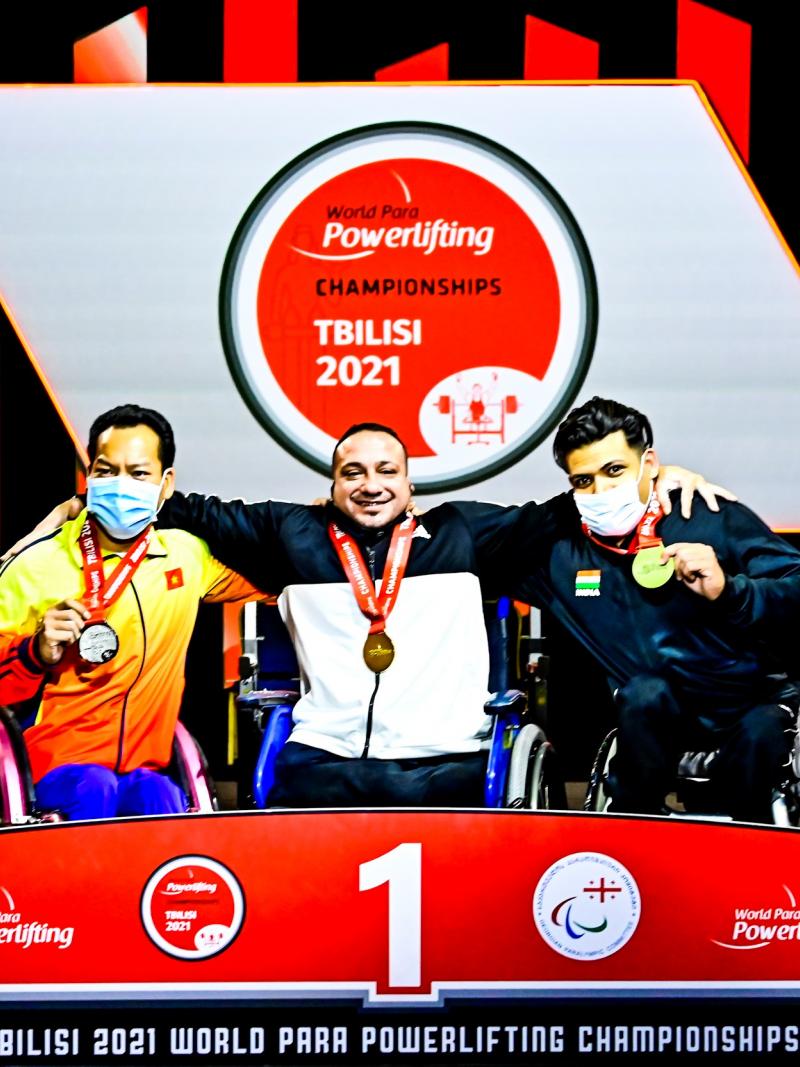 Three athletes hugging each other on the podium while posing for a photo.