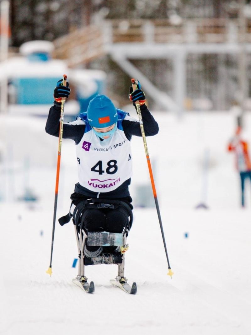 A sit skier competing in the cross-country competition pushing herself forward with two sticks