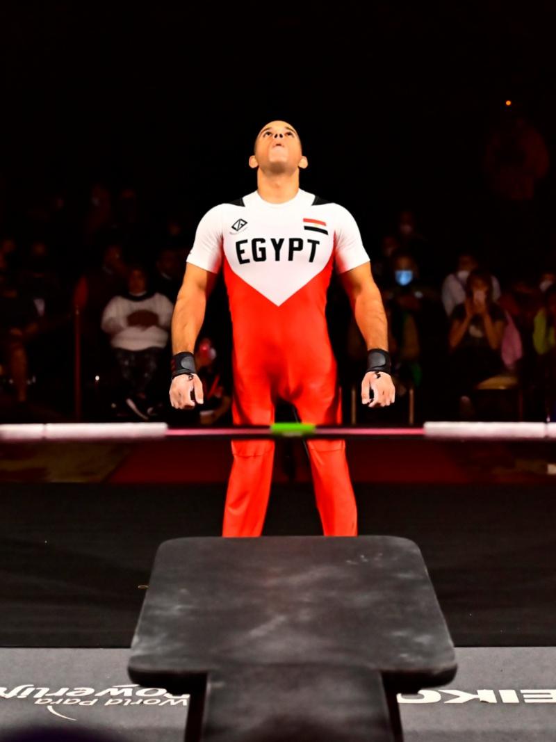 A man  looking up and standing in front of a bench press in a Para powerlifting