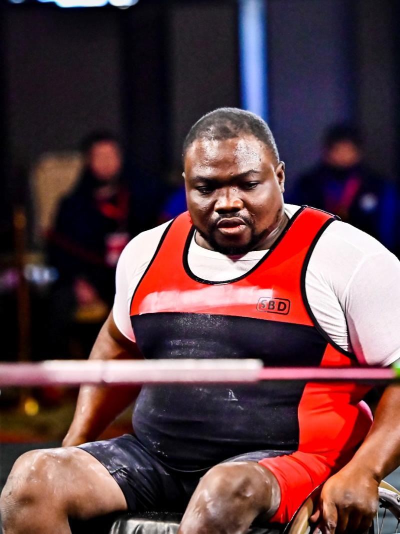 A man in a wheelchair in front of the bench concentrating before the lift