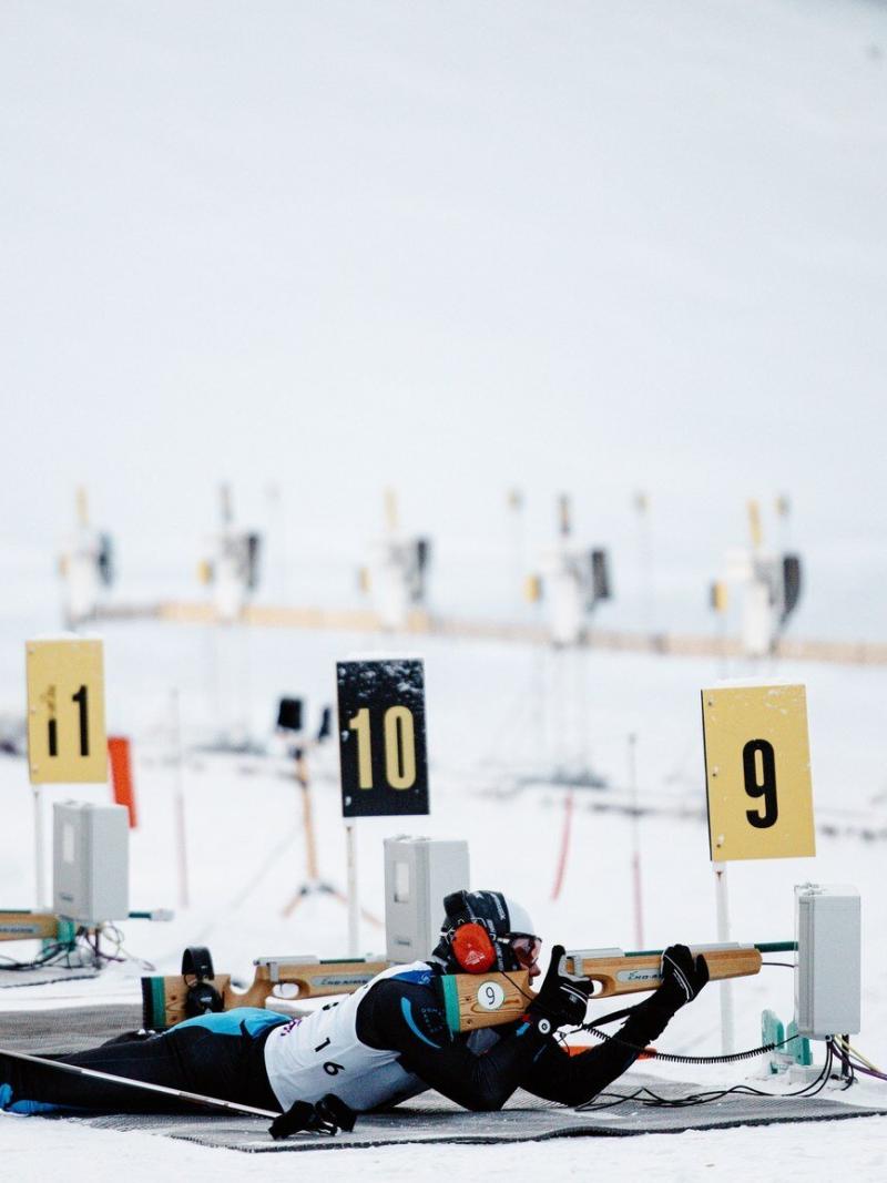 A man lying on the shooting range with a range and aiming.