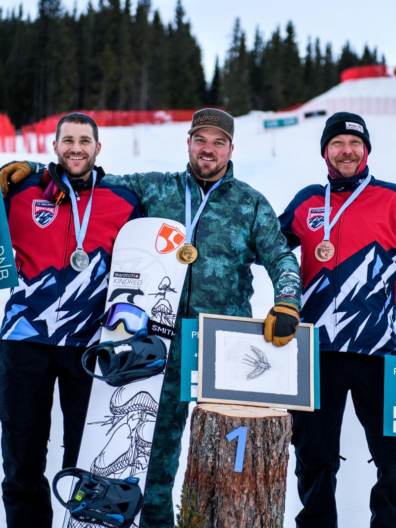 Three male snowboarders in a medal ceremony on the snow