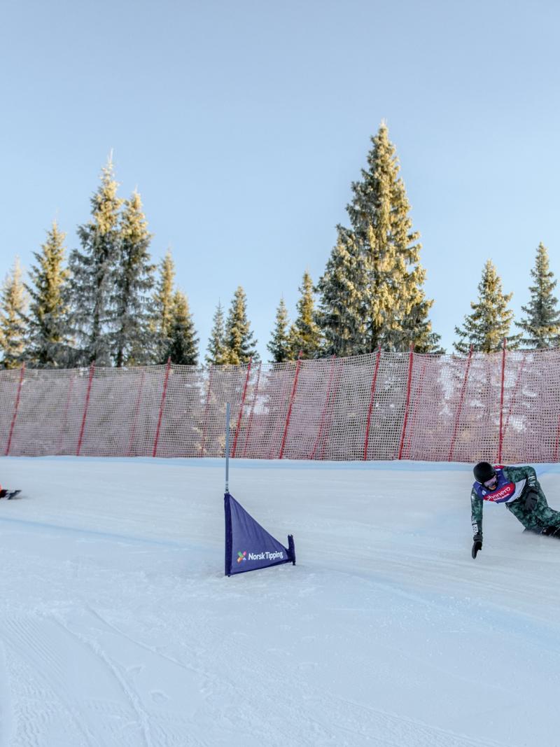 A male snowboarder ahead of three competitors in a snowboard cross