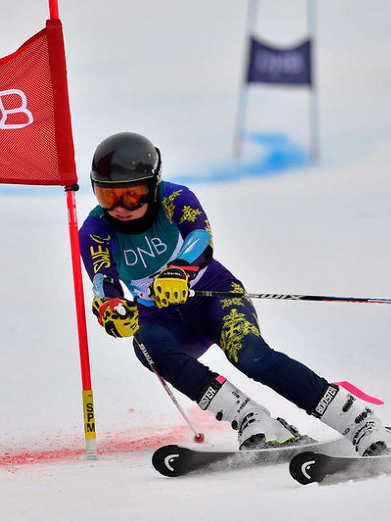 A female Para alpine skier crossing a red gate on a parallel event 