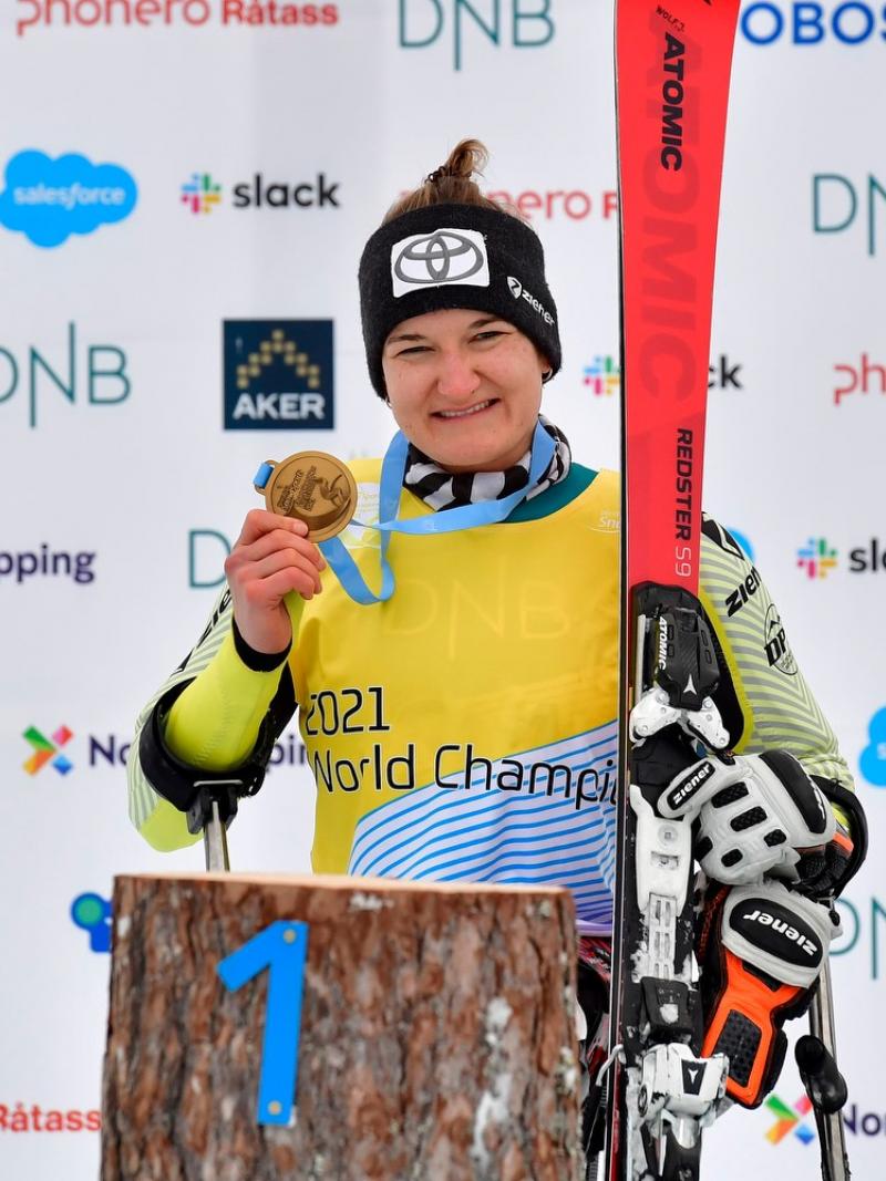 A female skier showing her gold medal in a medal ceremony
