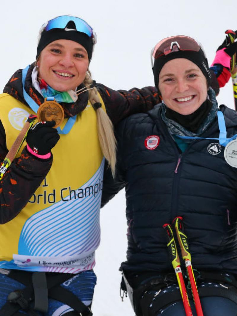 Two smiley women showing their medals in a snow sport competition