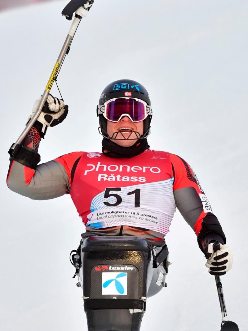 A male sit-skier celebrating in the snow