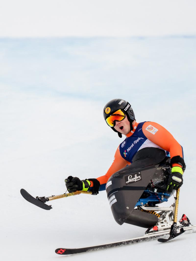 A sit-skier making a turn in a Para alpine skiing competition
