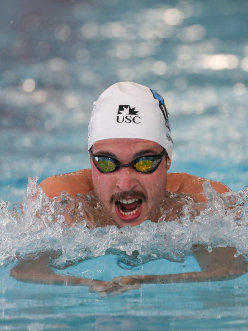 A man with a moustache swimming in the pool.