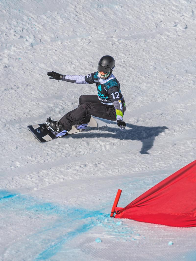 A man on a snowboard with his arms stretched going into the curve.