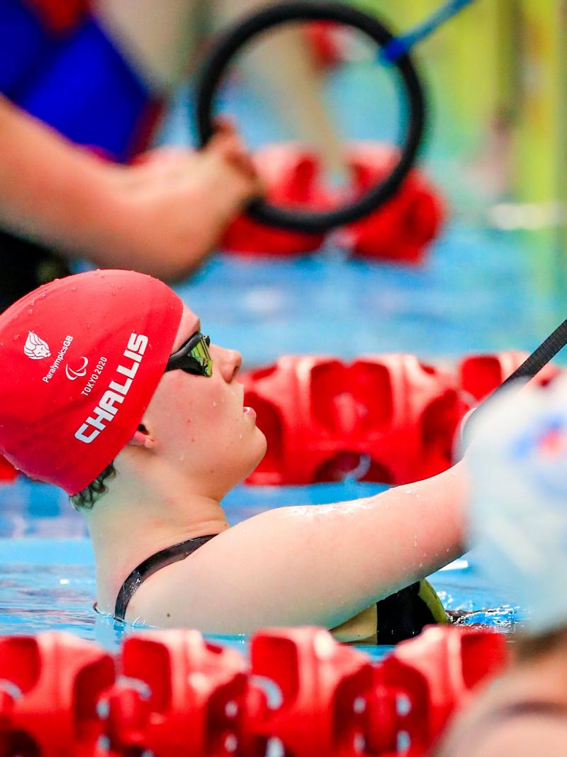 A female swimmer in the pool, hanging onto a rope with both hands before the race start.