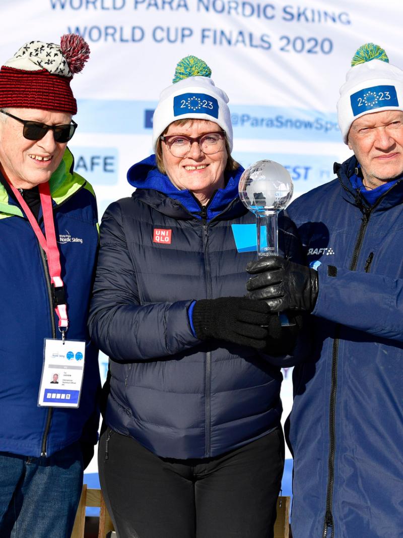 A man standing next to a woman and another man holding a trophy 