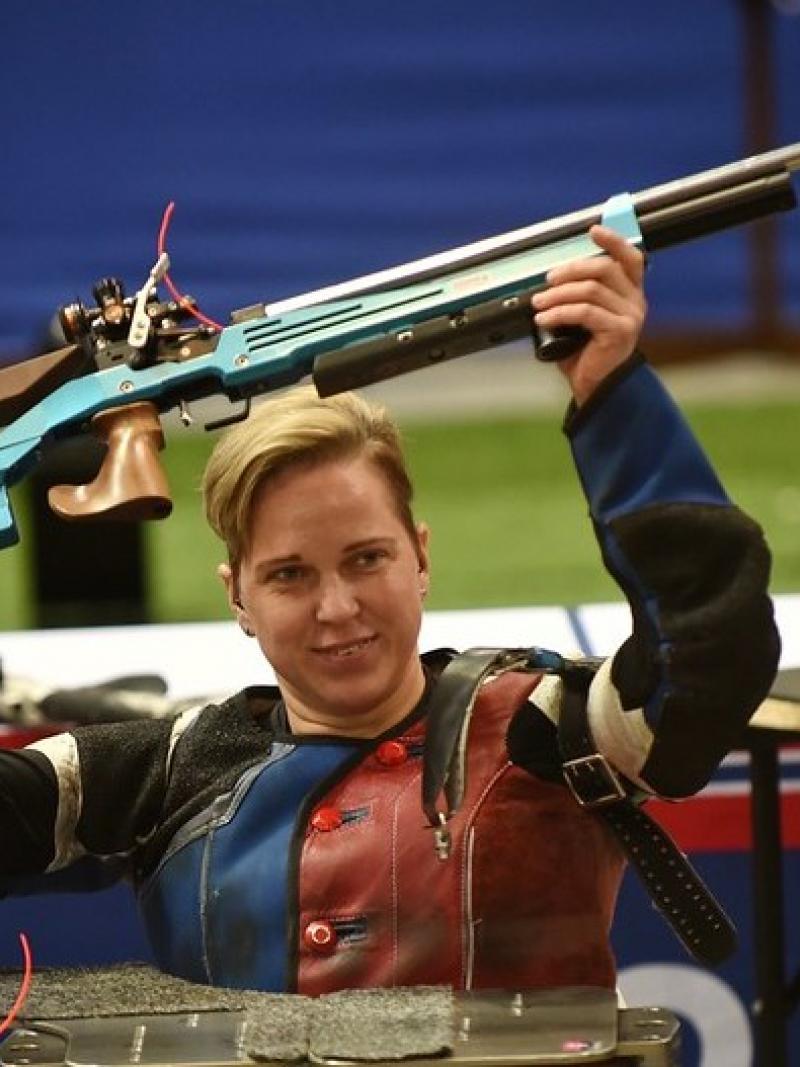 A female shooter raising her competition rifle above her head