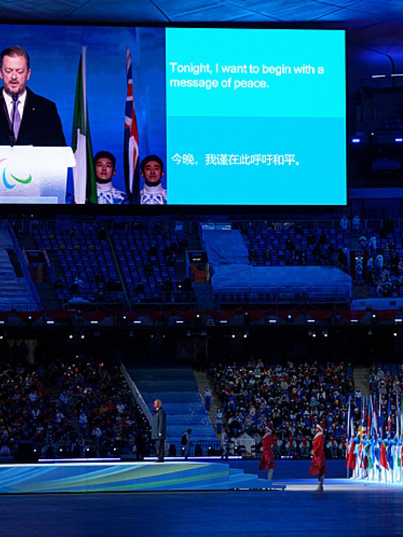 Andrew Parsons is pictured on a large screen at the Opening Ceremony of Beijing 2022 alongside a sentence of his speech which reads: 'tonight I want to begin with a message of peace'