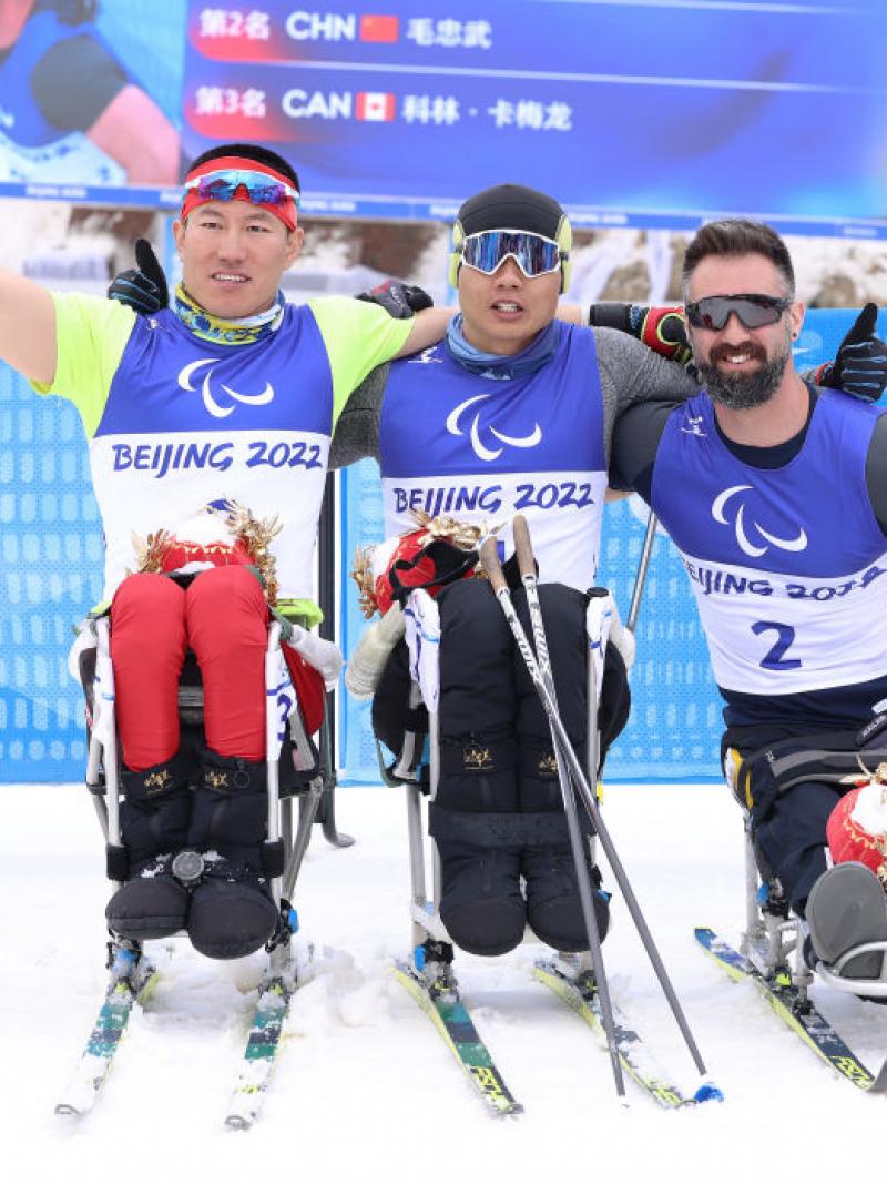 Gold medallist Zheng Peng of China (C), countrymate silver medallist Mao Zhongwu (L) and bronze medallist Collin Cameron of Canada (R) pose during Men's Sprint Sitting Final flower ceremony in the Beijing 2022 Paralympics Winter Games at Zhangjiakou National Biathlon Centre.