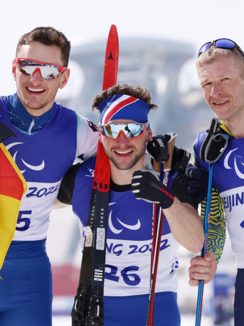 Gold medallist Benjamin Daviet of France (C), silver medallist Marco Maier of Germany (L) and bronze medallist Grygorii Vovchynskyi of Ukraine (R) celebrate their win in the Men's Sprint Free Technique Standing in the Beijing 2022 Paralympic Winter Games at Zhangjiakou National Biathlon Centre. 