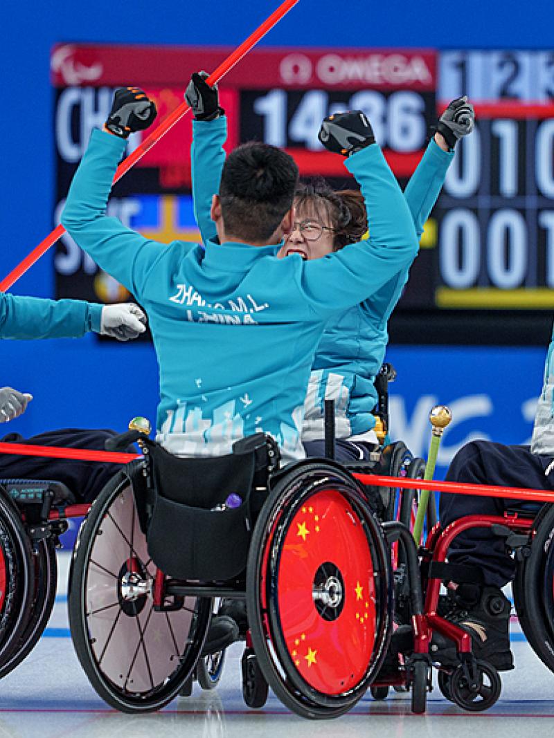 The Chinese wheelchair curling team raise their arms in the air in celebration