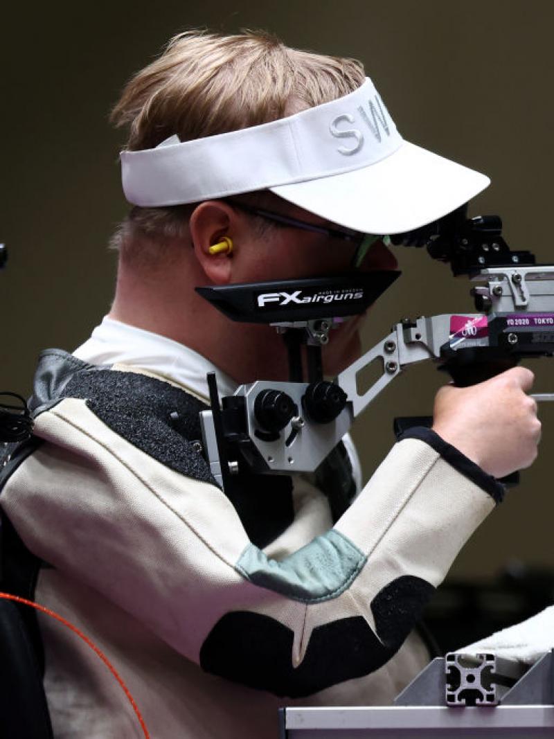 A man in a power chair competing in a shooting event with a rifle