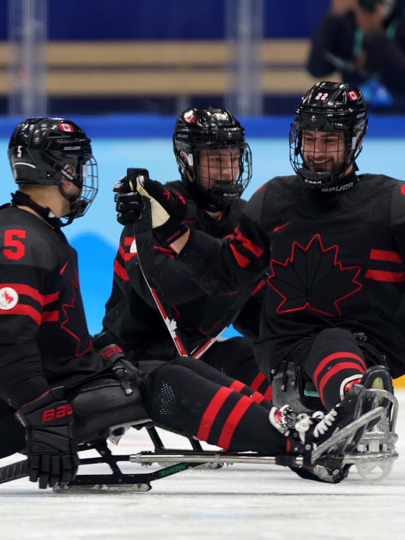 Three Para ice hockey players smiling to each other.
