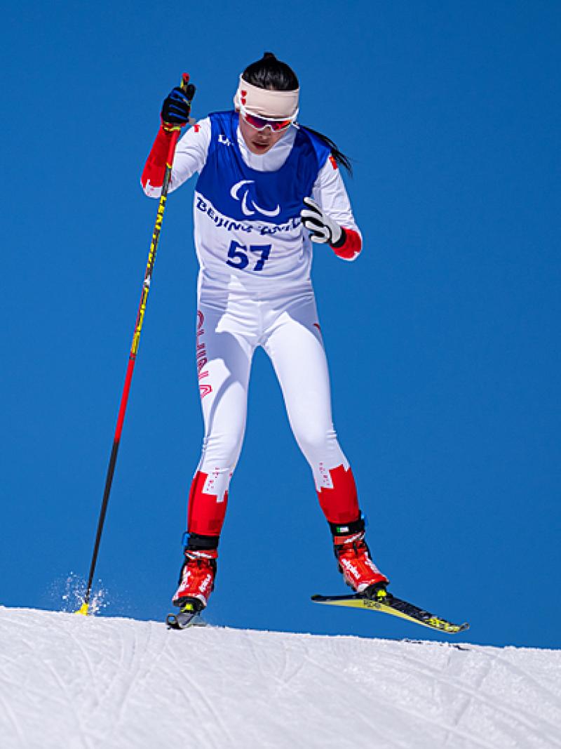 Yujie Guo of China looks determined as she skis in the women's sprint standing in front of clear blue skies