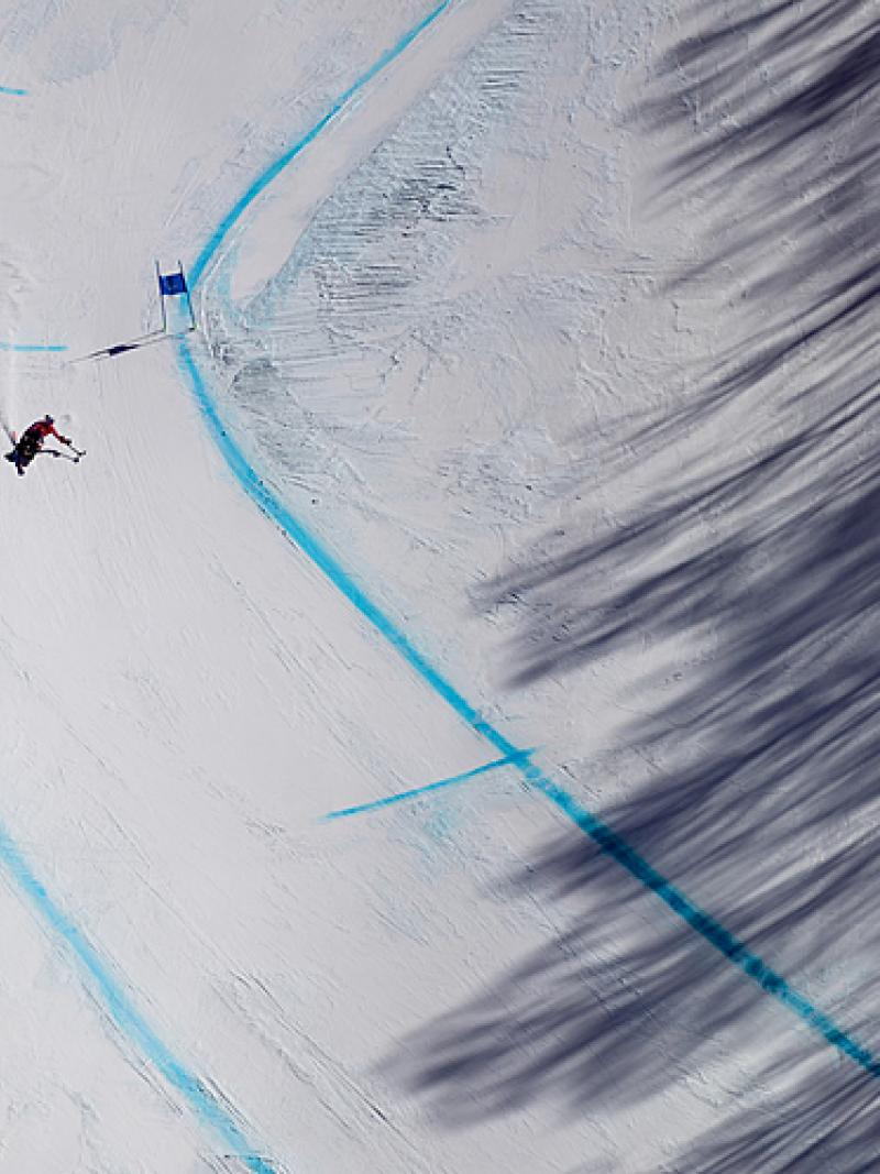 A Para Alpine sit-skier makes their way down the course during training in the shadow of the trees