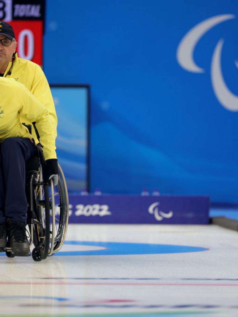 A Swedish wheelchair curler pushes the stone forward
