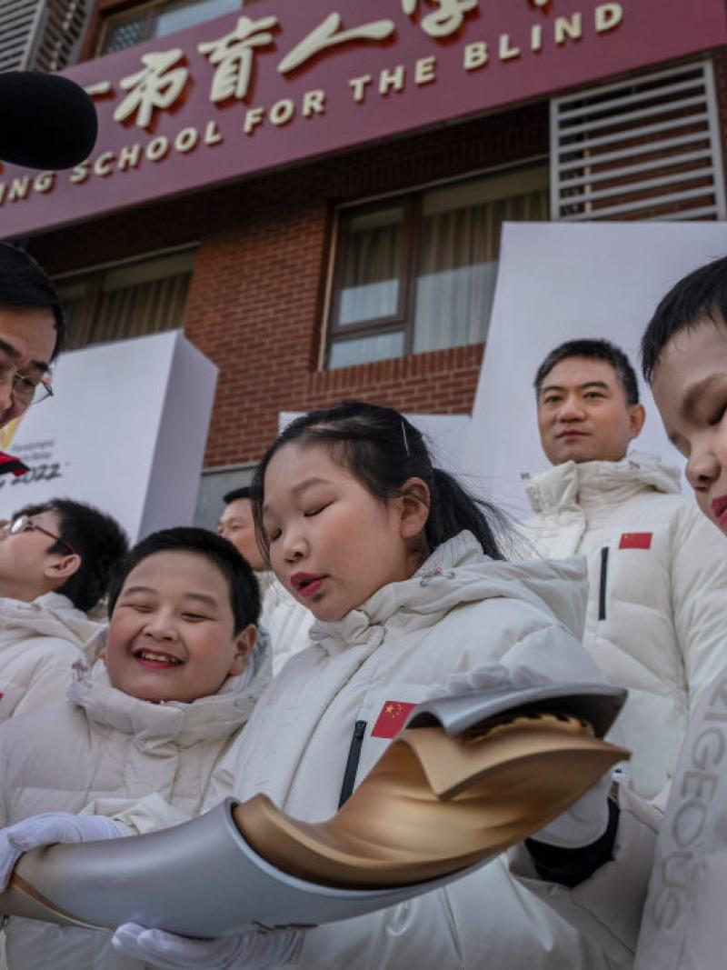 Students and choir members from the Beijing School for Blind feel and touch the torch as torchbearer Dr. Yao Yufeng (L) holds it out after the start of the Beijing 2022 Winter Paralympics Torch Relay.