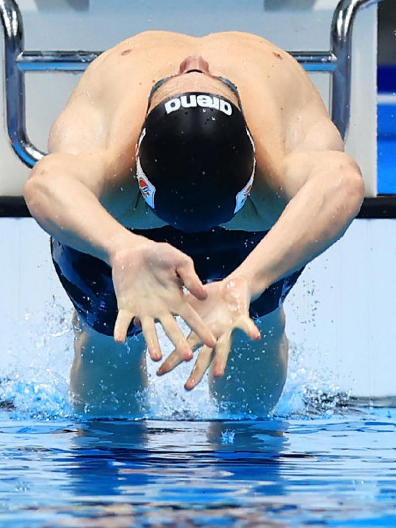 A male swimmer in the starting block in a backstroke race