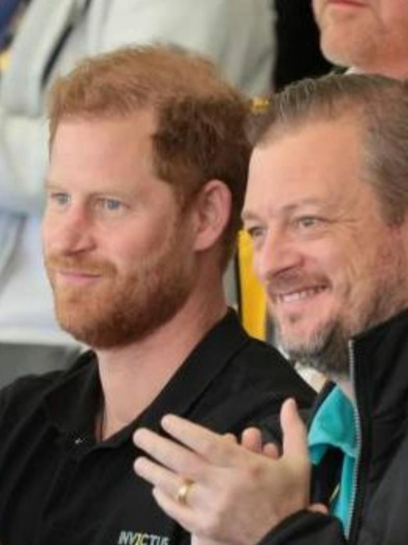 Prince Harry and IPC President Andrew Parsons sitting next to each other and clapping while watching the Invictus Games