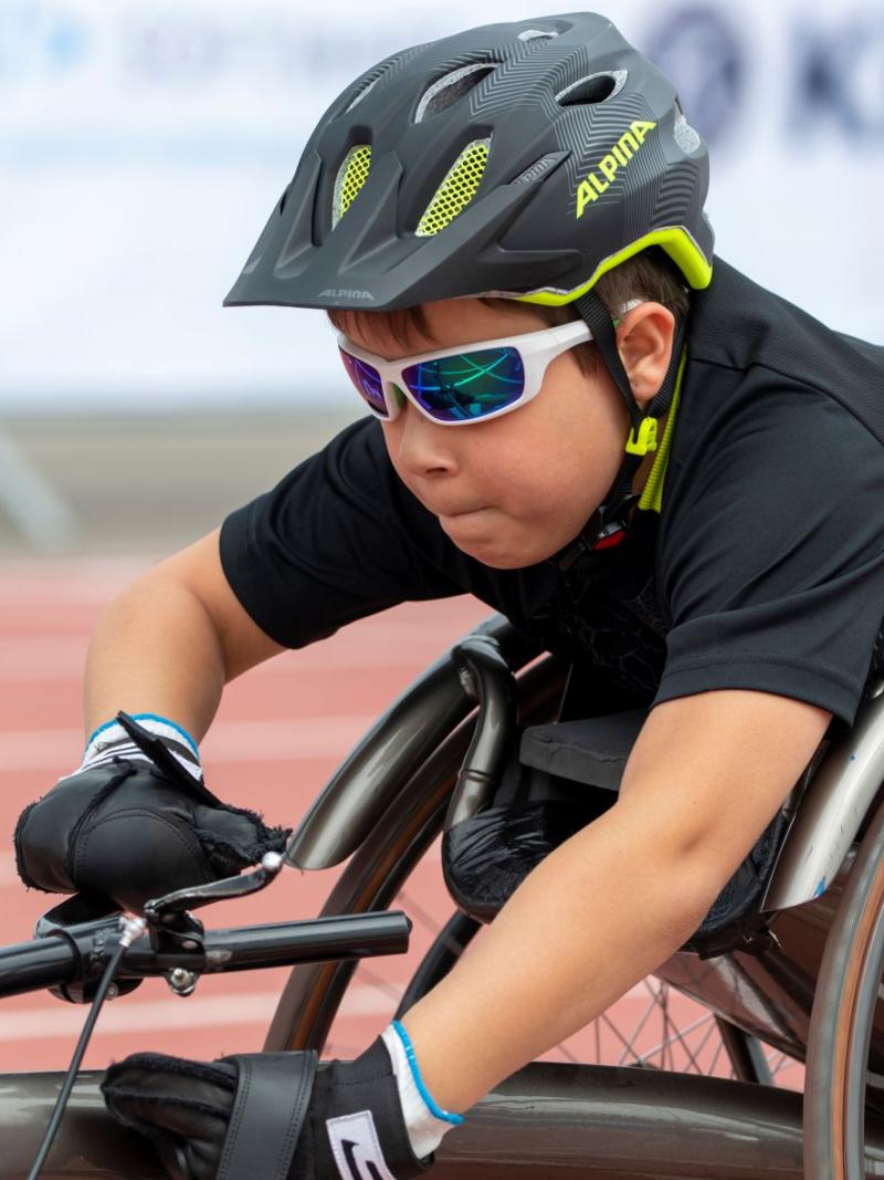 A close-up of Adrian Ruf as he pushes forward in his racing wheelchair with a look of determination on his face.