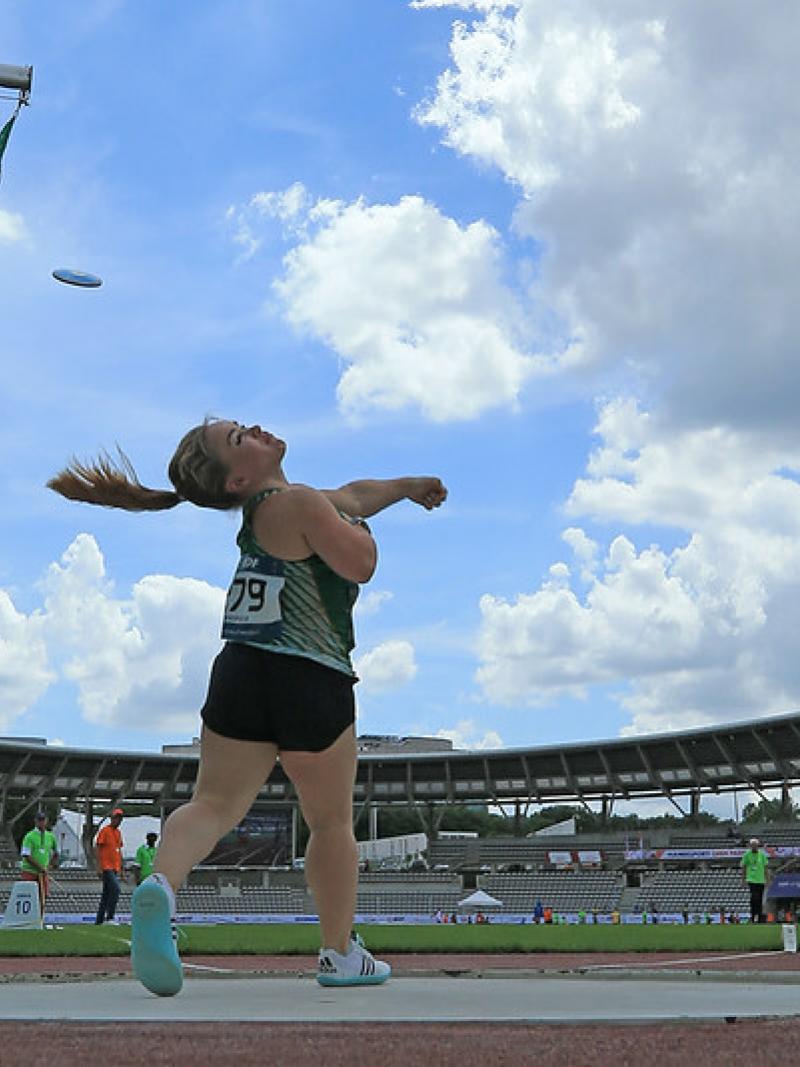 Image of a female Para Athletics in competition throwing a discus