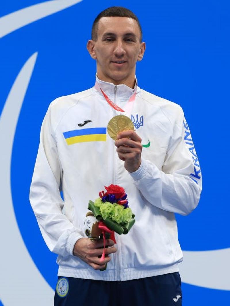 Image of a male Para swimmer in the podium with his gold medal and his flowers
