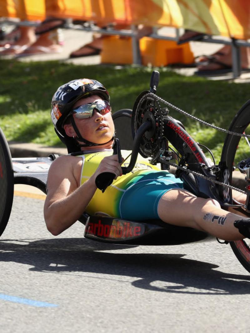 Lauren Parker, wearing the Australian kit but no shoes, rides her handbike on a cement road during the women's PTWC final at the 2018 Commonwealth Games.