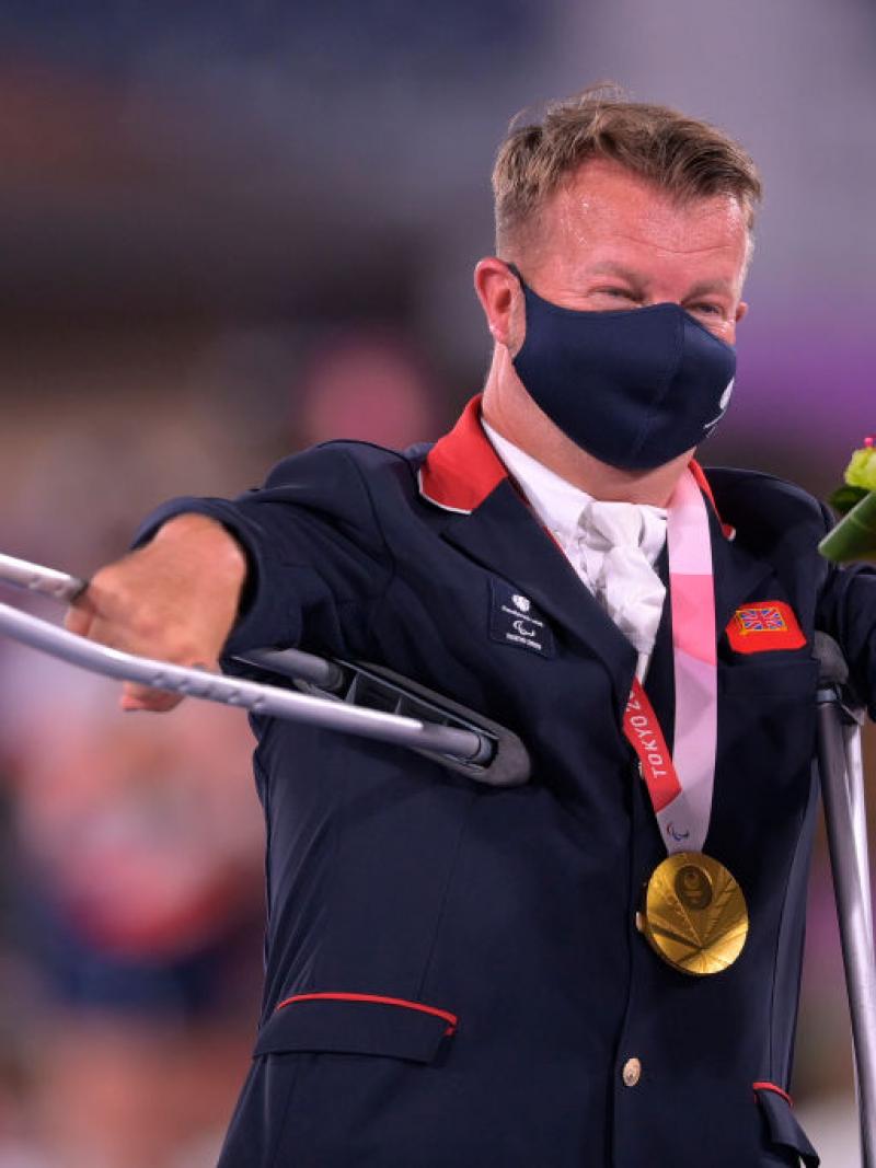 Sir Lee Pearson waves his crutch in celebration after receiving his gold medal at a victory ceremony in Tokyo.