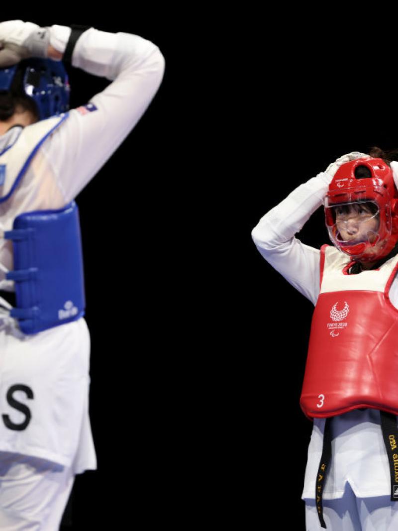 Australia's Janine Watson and Japan's Shoko Ota face each other as they adjust their helmets, preparing for their repechage match.