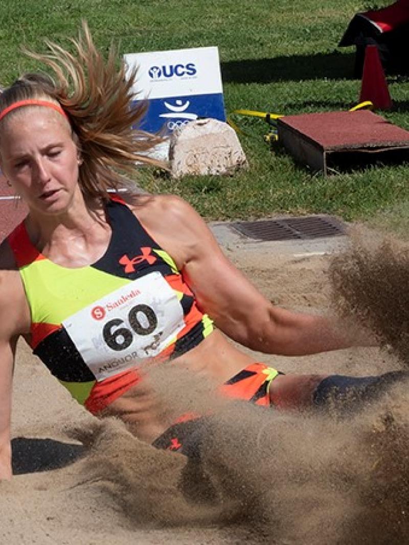 A woman landing in a sand box in a long jump competition