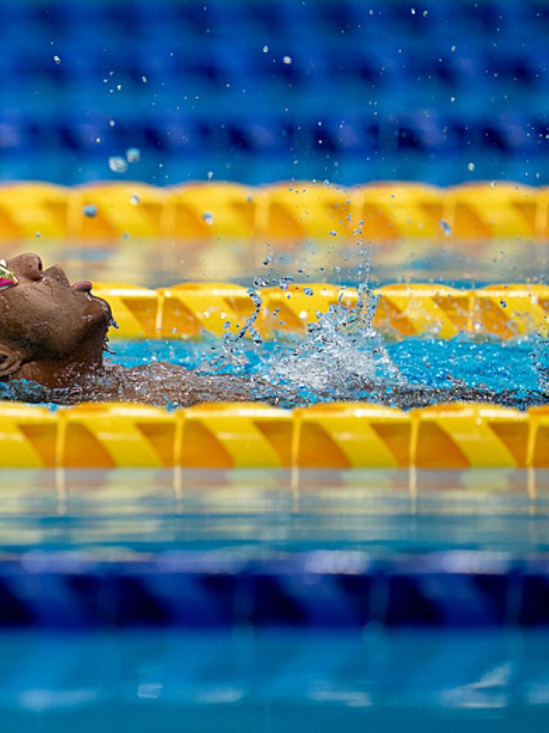 A male Para swimmer swimming backstroke in a pool