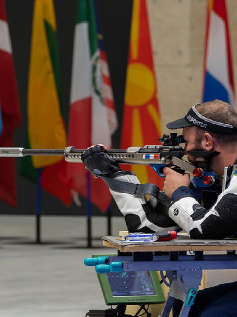 A male athlete shooting with a rifle in a shooting Para sport competition