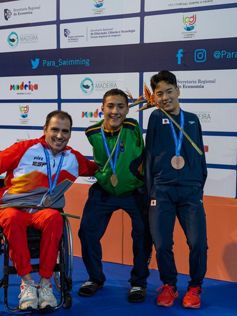Three men with disabilities on a podium with their medals