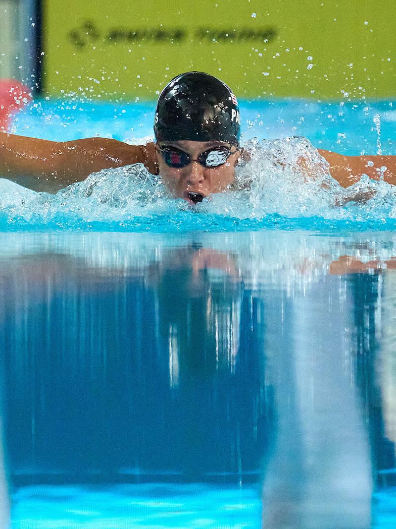 A female swimmer in a black cap swimming butterfly