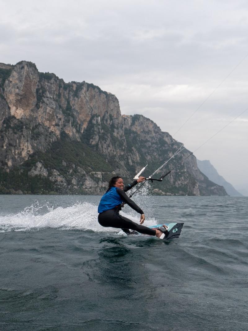 A female kiteboarder smiles as she makes her way across the water.