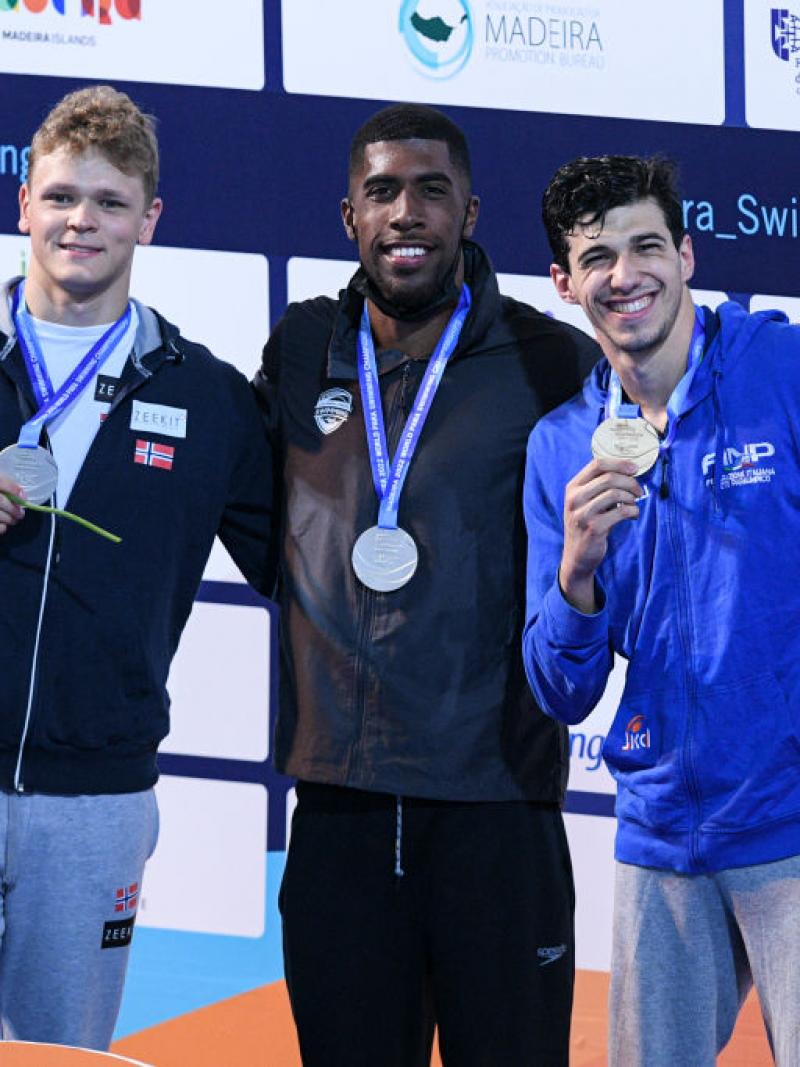 Three men standing on a podium with their medals