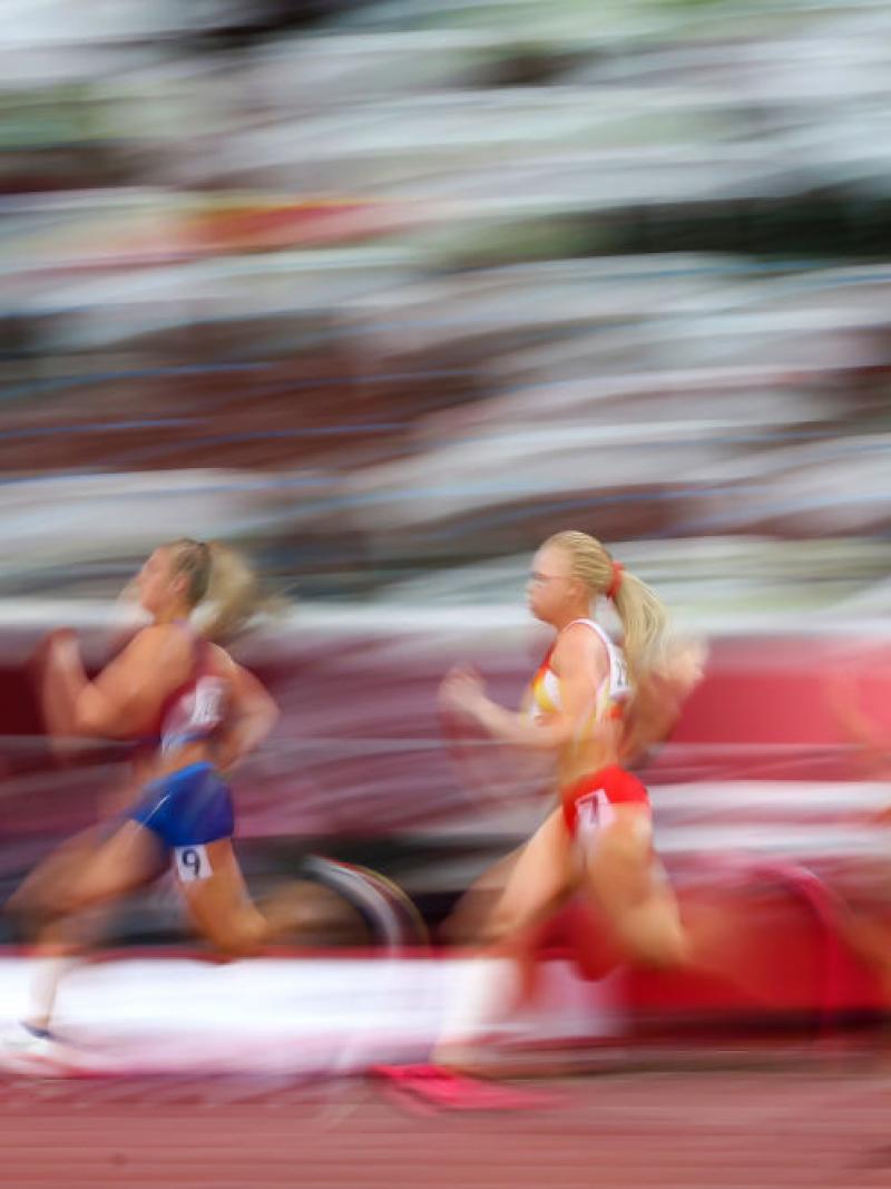 A blurred image of four women competing in an athletics track