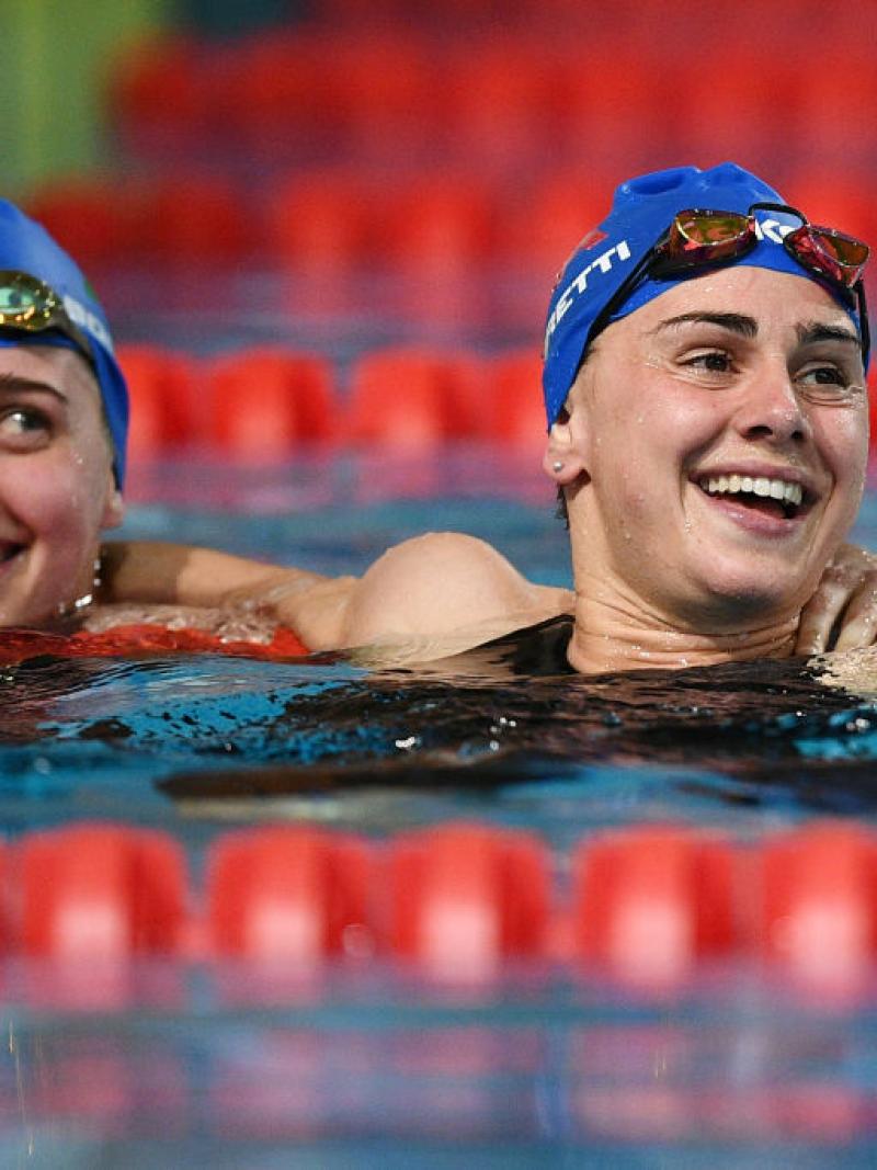 Two female swimmers with Italian caps smiling in a pool