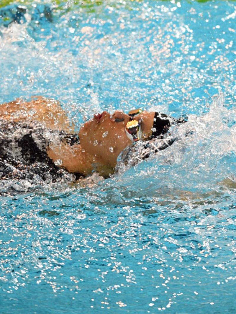A female athlete swimming backstroke in a pool