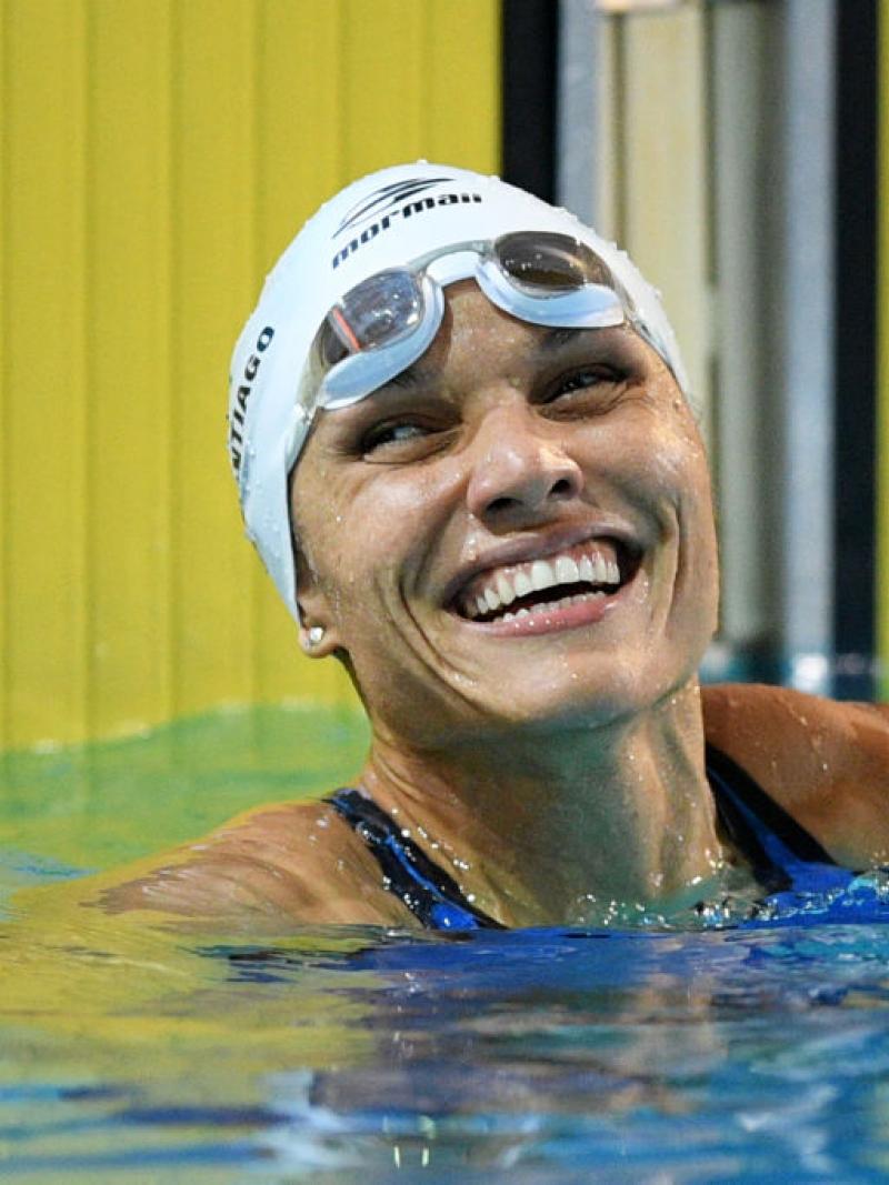 A female swimmer smiling from inside a competition pool