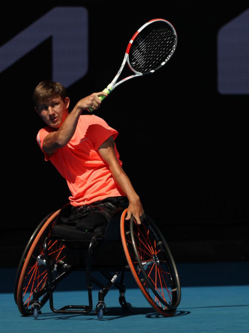 Niels Vink plays in an Australian Open match, his right hand holding his racquet and the other directing his wheelchair.