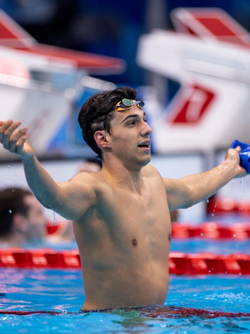 A male celebrates by stretching his hands out after a race.