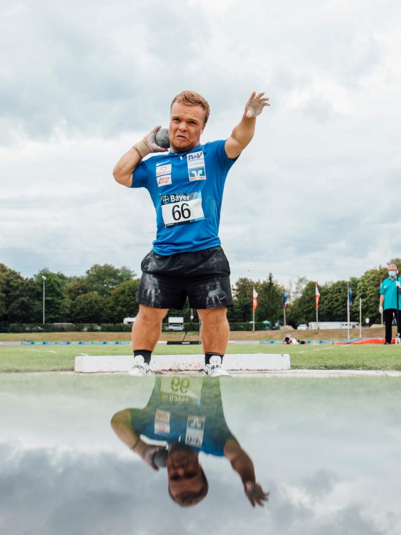 A short stature man competing in shot put
