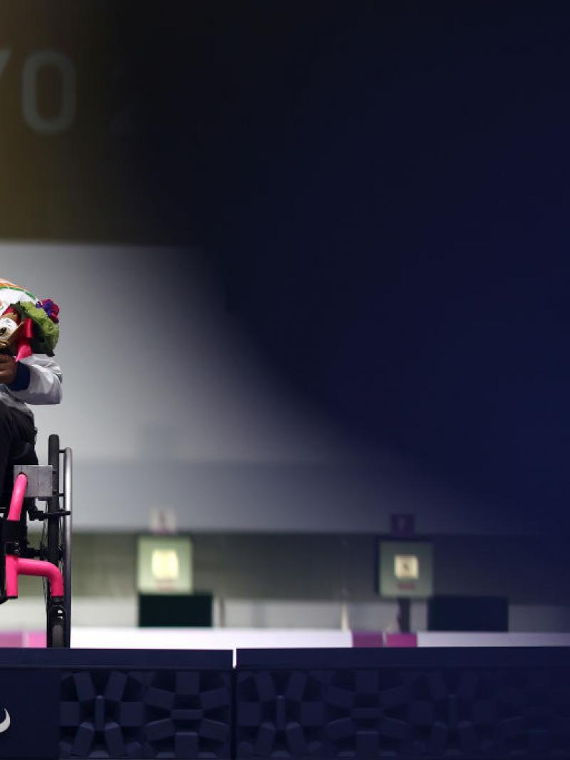 Avani Lekhara sits in her wheelchair on the Tokyo 2020 podium with a gold medal around her neck.